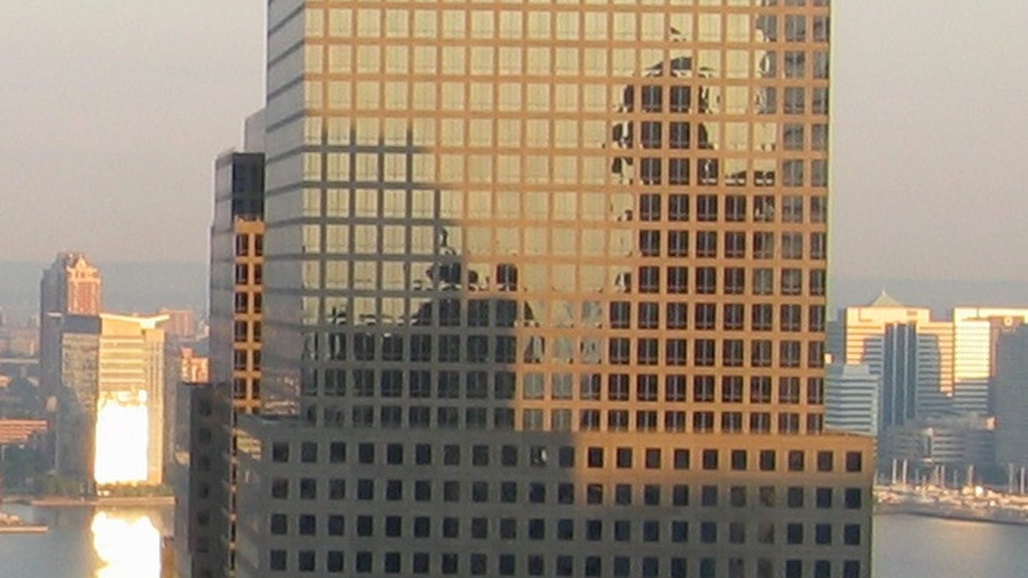 A tall office tower with a pyramid-shaped top beside other buildings in Lower Manhattan