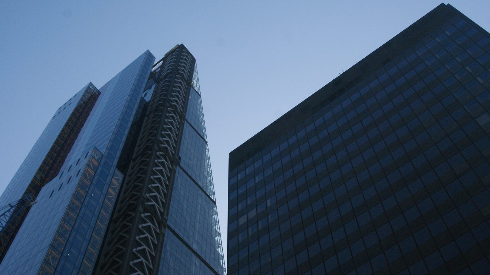 The dark glass Aviva Tower next to the Heron Tower against a blue sky in the City of London