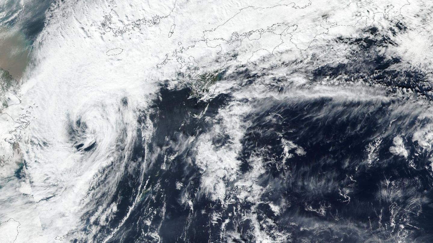 Satellite view of a swirl of white cloud over the dark blue sea south-west of Japan, with thick cloud covering Kyushu and western Japan at the top