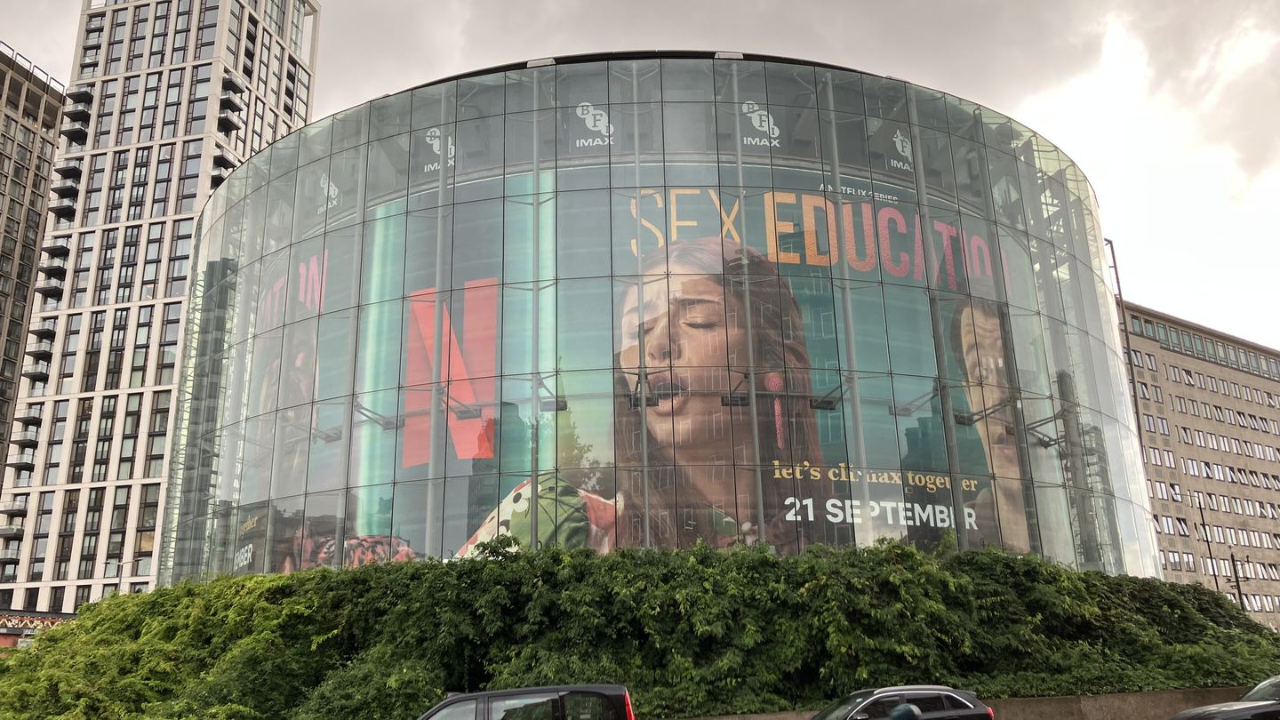 The round glass-walled BFI IMAX cinema building in London's South Bank, surrounded by greenery and tall buildings