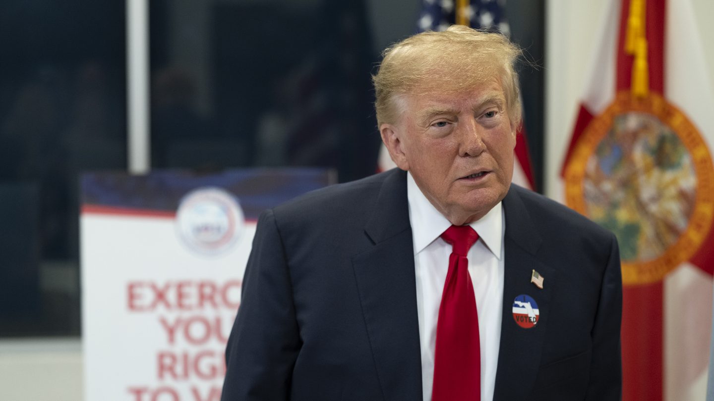 President Donald Trump wearing an 'I voted' sticker at an early voting site in West Palm Beach, Florida, next to a sign reading 'Exercise your right'