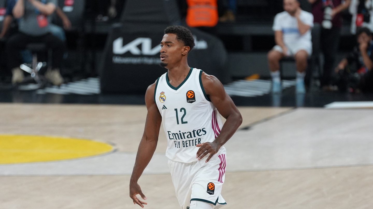 Real Madrid guard Théo Maledon bringing the ball up the court in Real Madrid's white kit