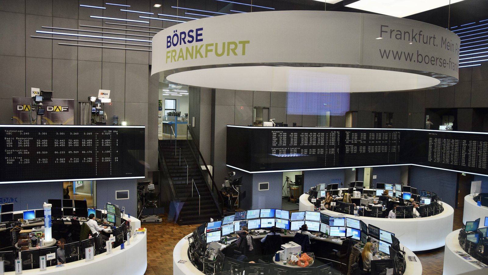 The trading floor of the Frankfurt Stock Exchange, with a round Börse Frankfurt sign above rows of trader desks and price boards