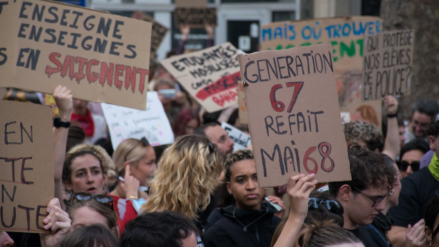 High-school and university students hold handwritten cardboard placards during a protest march in Paris