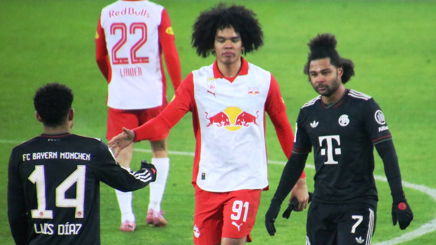 Bayern Munich players Serge Gnabry, number 7, and Luis Díaz, number 14, in black kits on the pitch next to a Salzburg player in red and white