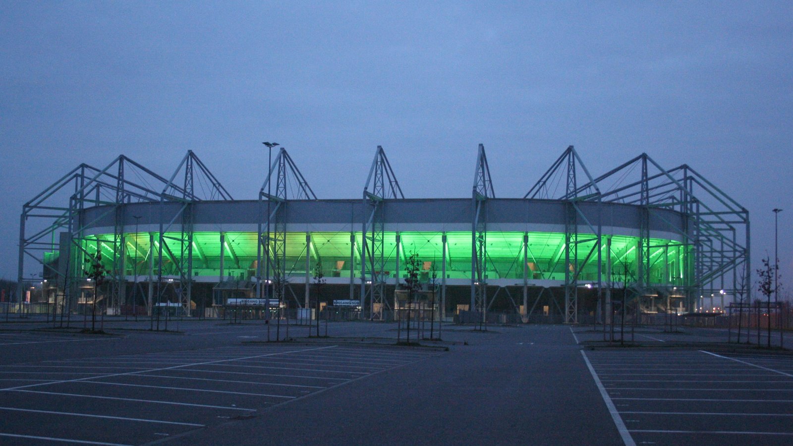 Exterior of the Borussia-Park stadium in Mönchengladbach at dusk, lit in green