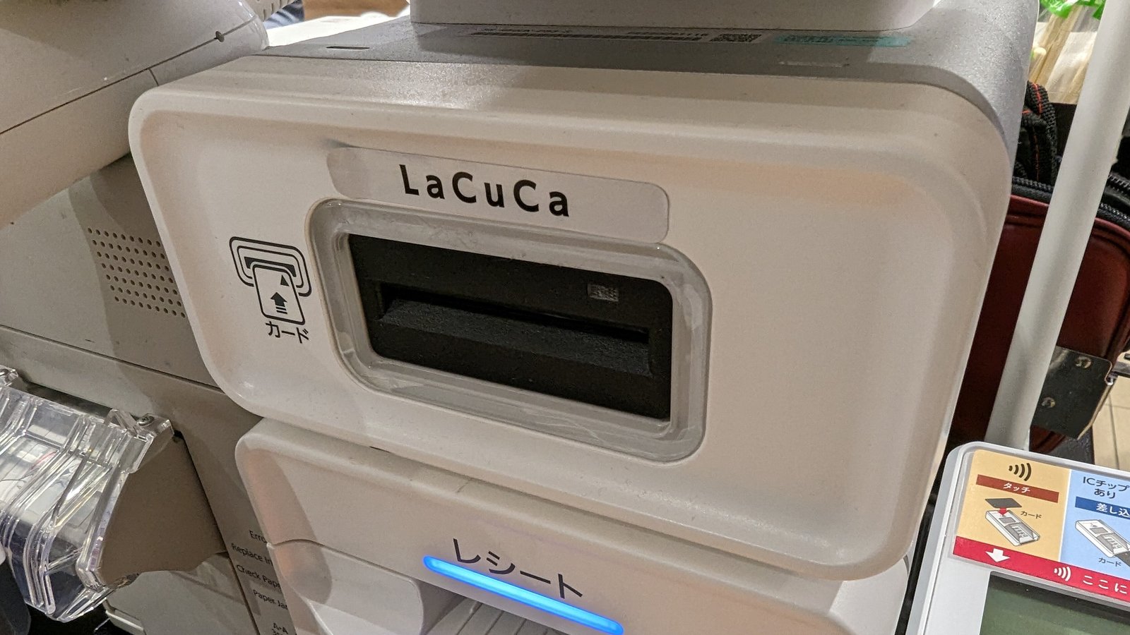 A white card payment terminal with a card slot at a supermarket checkout