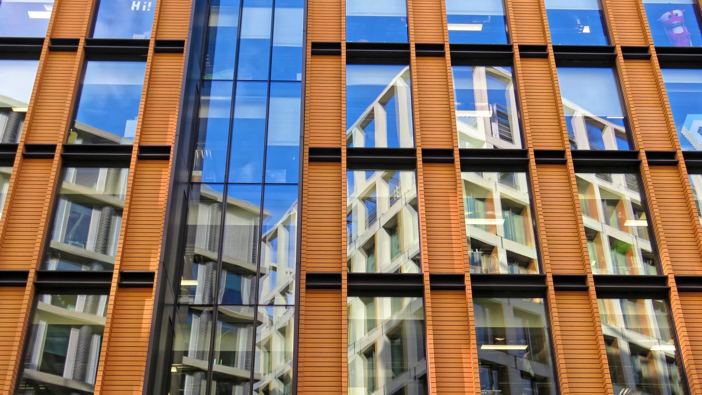 Orange terracotta-clad facade with large blue glass windows of the Google building at 6 Pancras Square in London