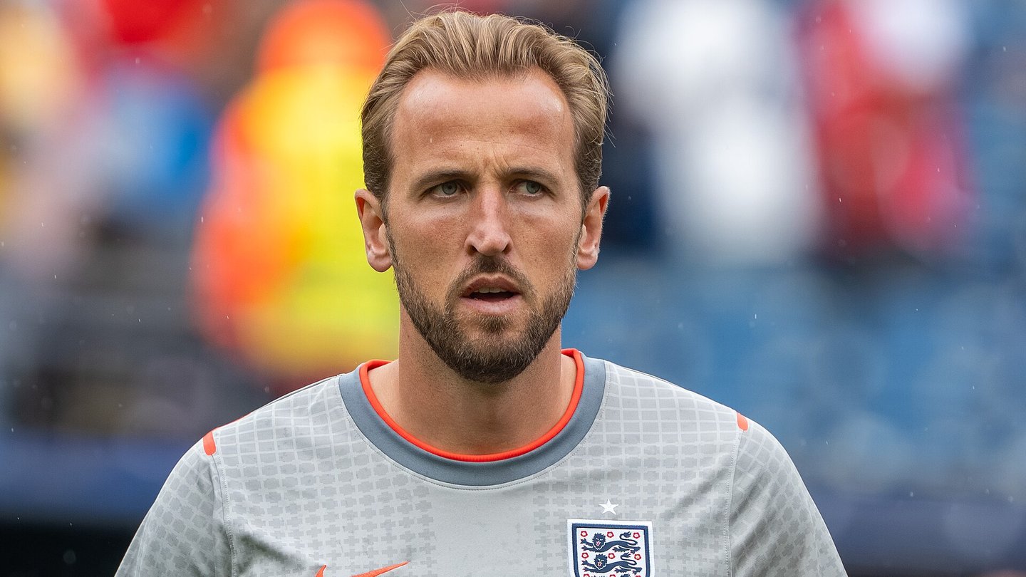 Harry Kane in a grey England warm-up shirt with the Three Lions badge, in a stadium