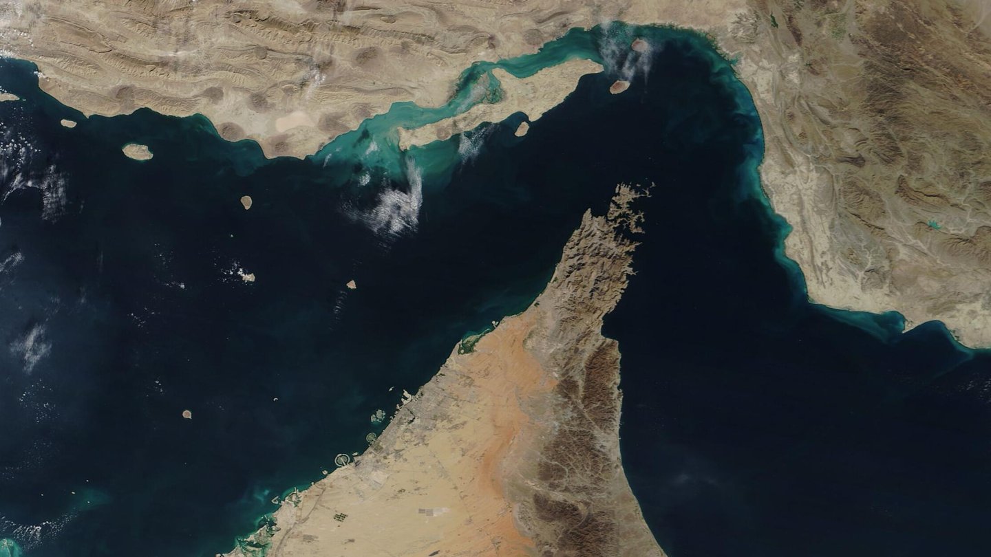 Satellite view of the Strait of Hormuz, with Oman's Musandam peninsula reaching north between the Persian Gulf and the Gulf of Oman, and Iran's coast at the top