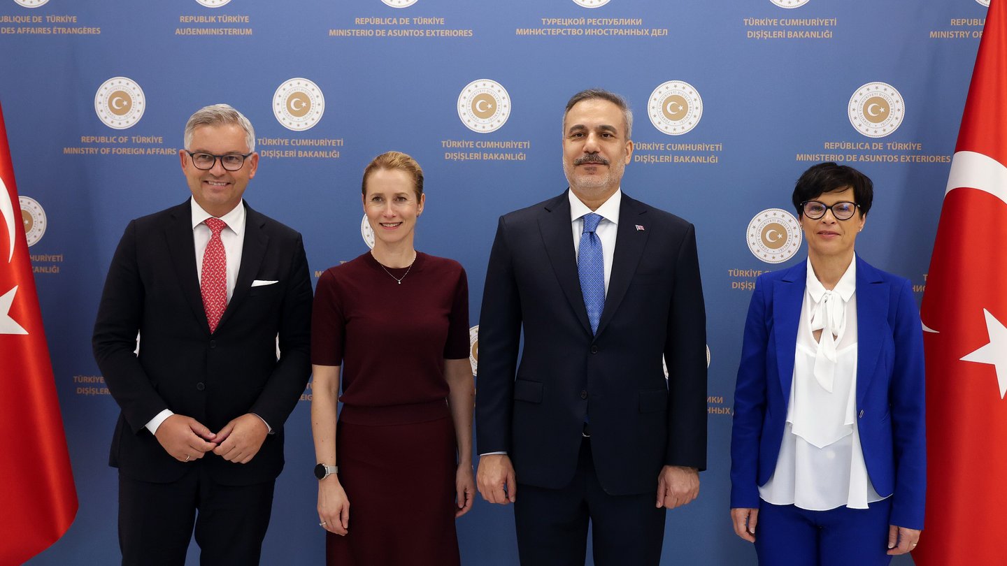 Turkish Foreign Minister Hakan Fidan standing with EU foreign policy chief Kaja Kallas and two other officials in front of Turkish flags