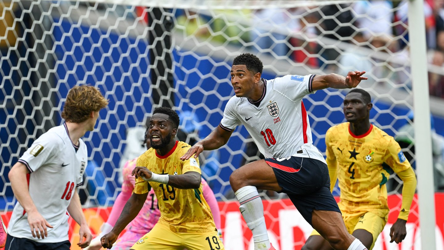 Iñaki Williams in a yellow Ghana shirt challenging for the ball with England players in white near the goal
