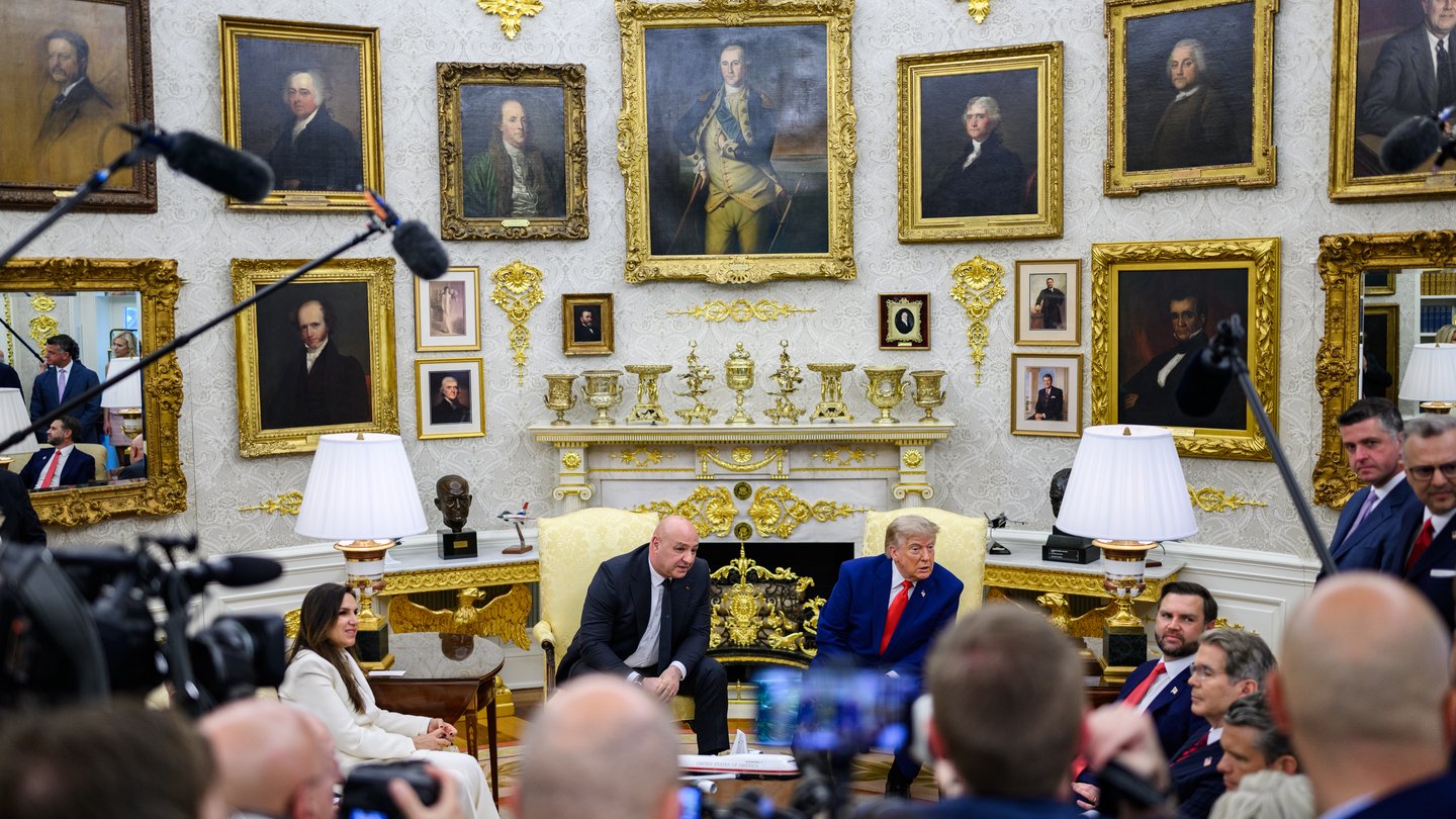 Lebanese President Joseph Aoun and US President Donald Trump seated in yellow armchairs in the Oval Office, surrounded by officials and reporters with cameras and microphones