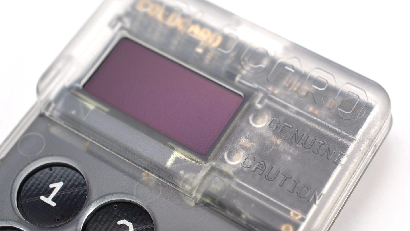 Close-up of a transparent hardware cryptocurrency wallet with a small screen and number buttons