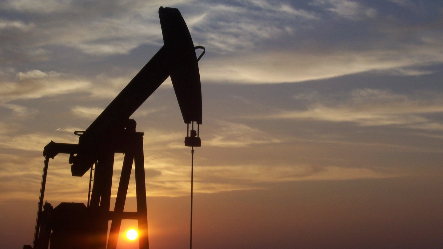 Silhouette of an oil pumpjack against an orange sunset sky in West Texas
