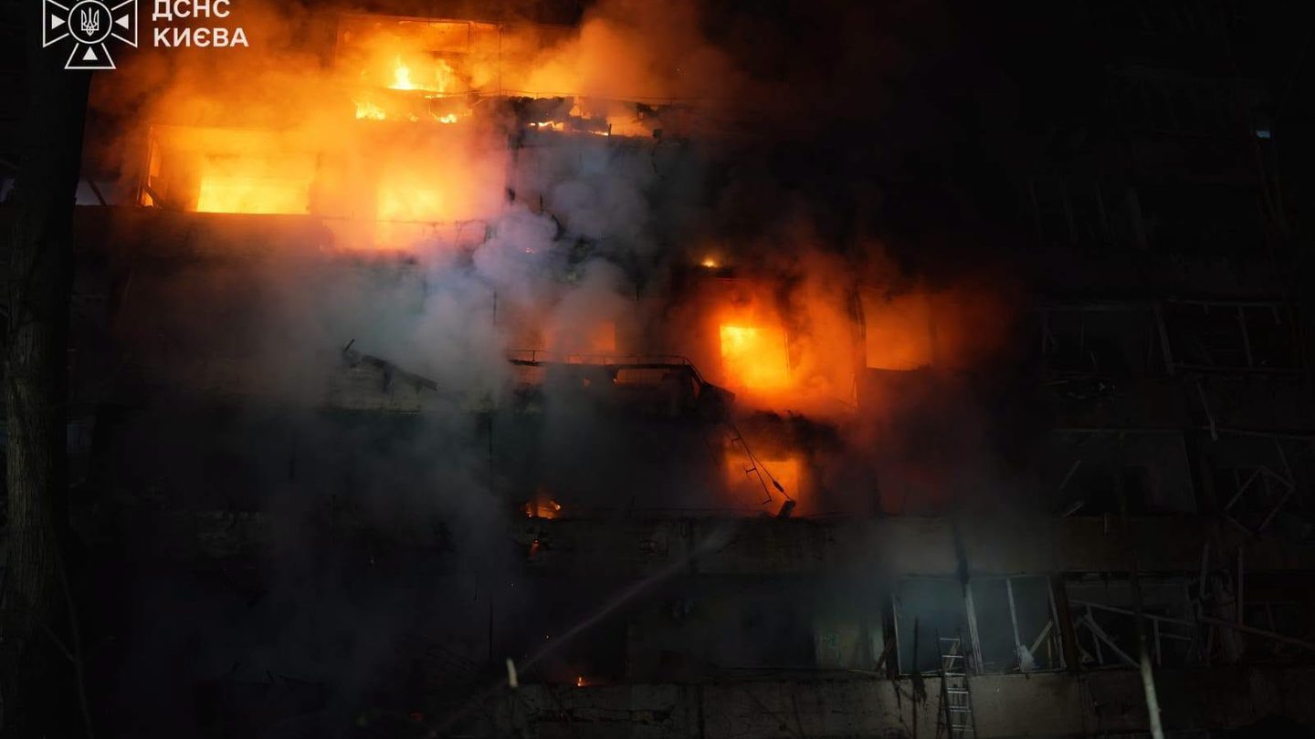 An apartment building on fire at night in Kyiv after a Russian attack, with flames visible through the windows