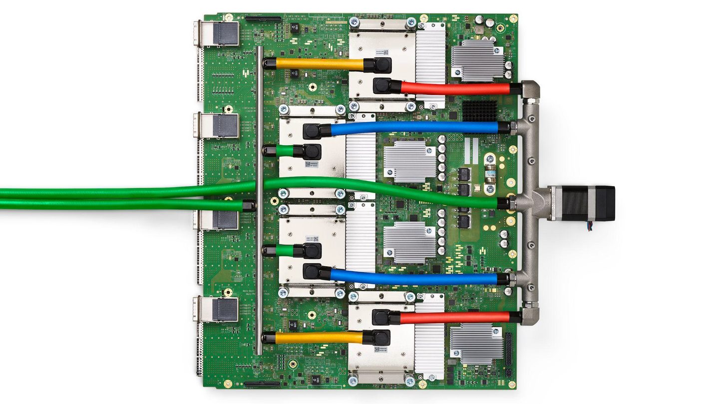 Overhead view of a green Google TPU v4 circuit board with four chip packages connected by colourful liquid-cooling hoses
