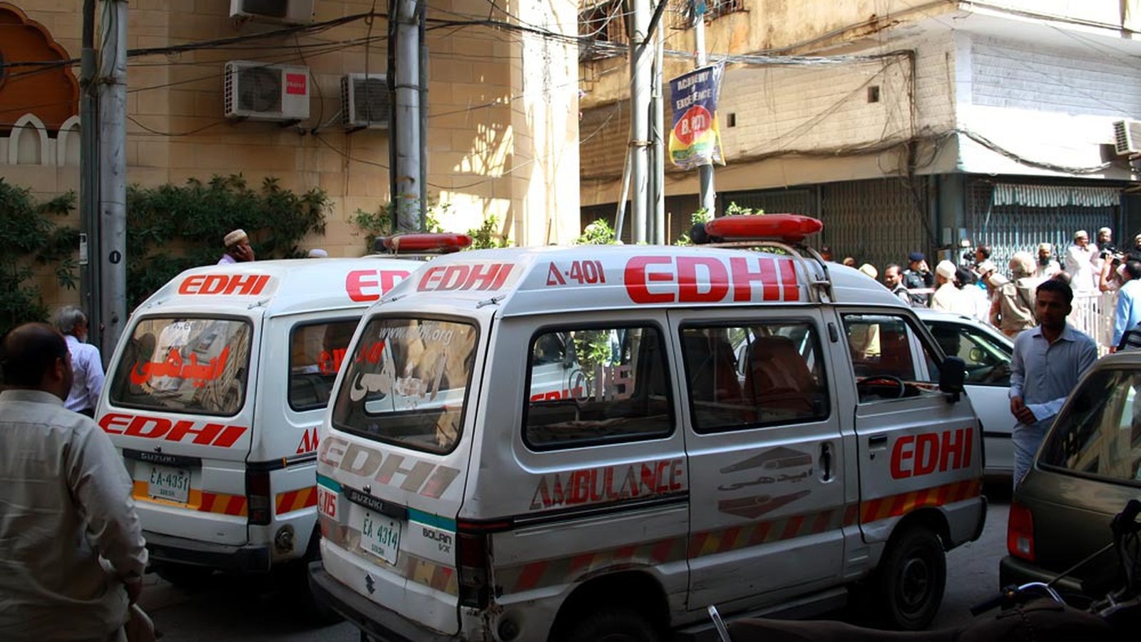 Two white Edhi Foundation ambulances with red lettering parked on a street in Karachi