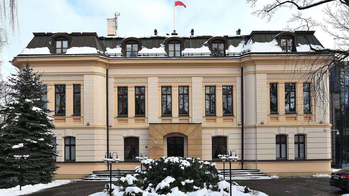 The cream-coloured front of the Constitutional Tribunal building in Warsaw, with a Polish flag on the roof and snow on the ground