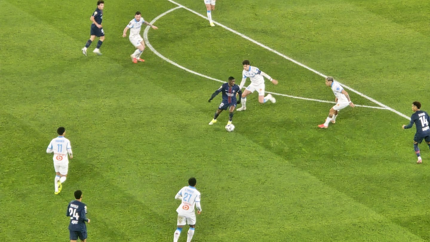 Paris Saint-Germain players in dark blue, including Senny Mayulu wearing number 24, in action against Marseille players in white at the Parc des Princes