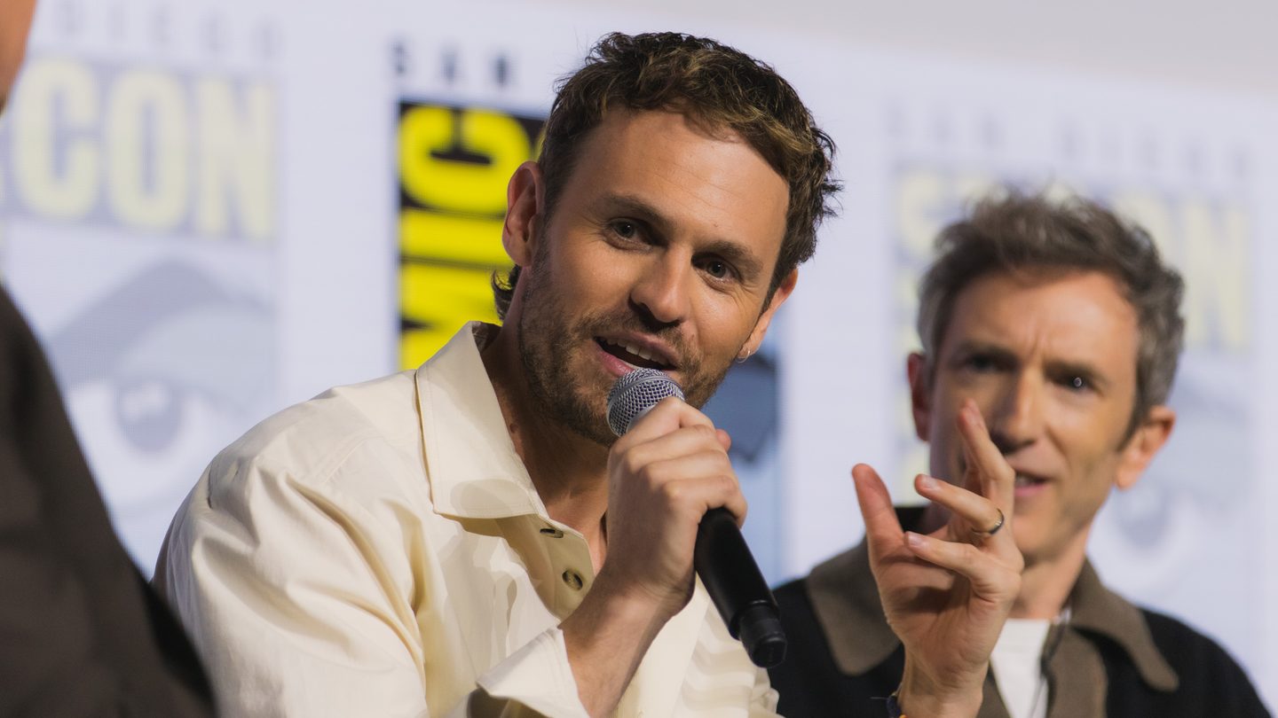 Actor Charlie Vickers speaking into a microphone on a panel at San Diego Comic-Con