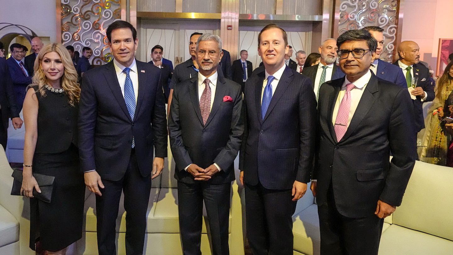 US Secretary of State Marco Rubio, in a dark suit and blue tie, stands with guests at a reception in Mumbai