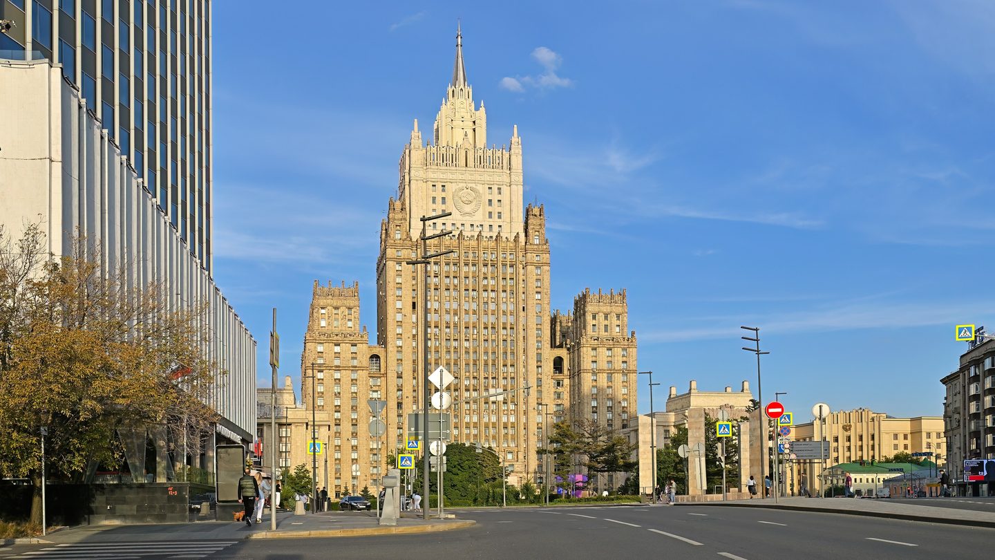 The tall Stalin-era Russian Foreign Ministry building on Smolenskaya-Sennaya Square in Moscow under a blue sky, with a wide road in the foreground