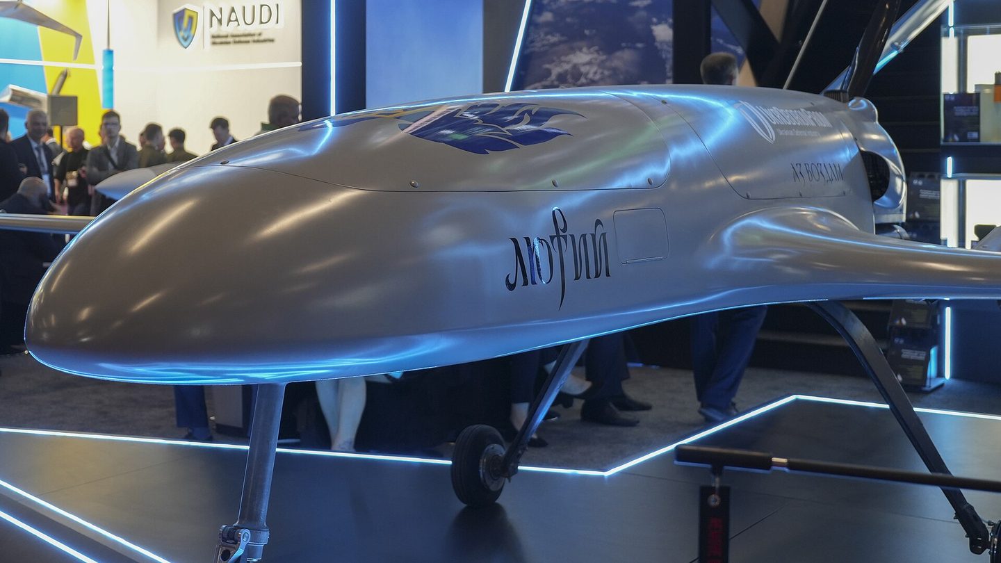 A silver Ukrainian Liutyi long-range strike drone on display at an arms exhibition stand