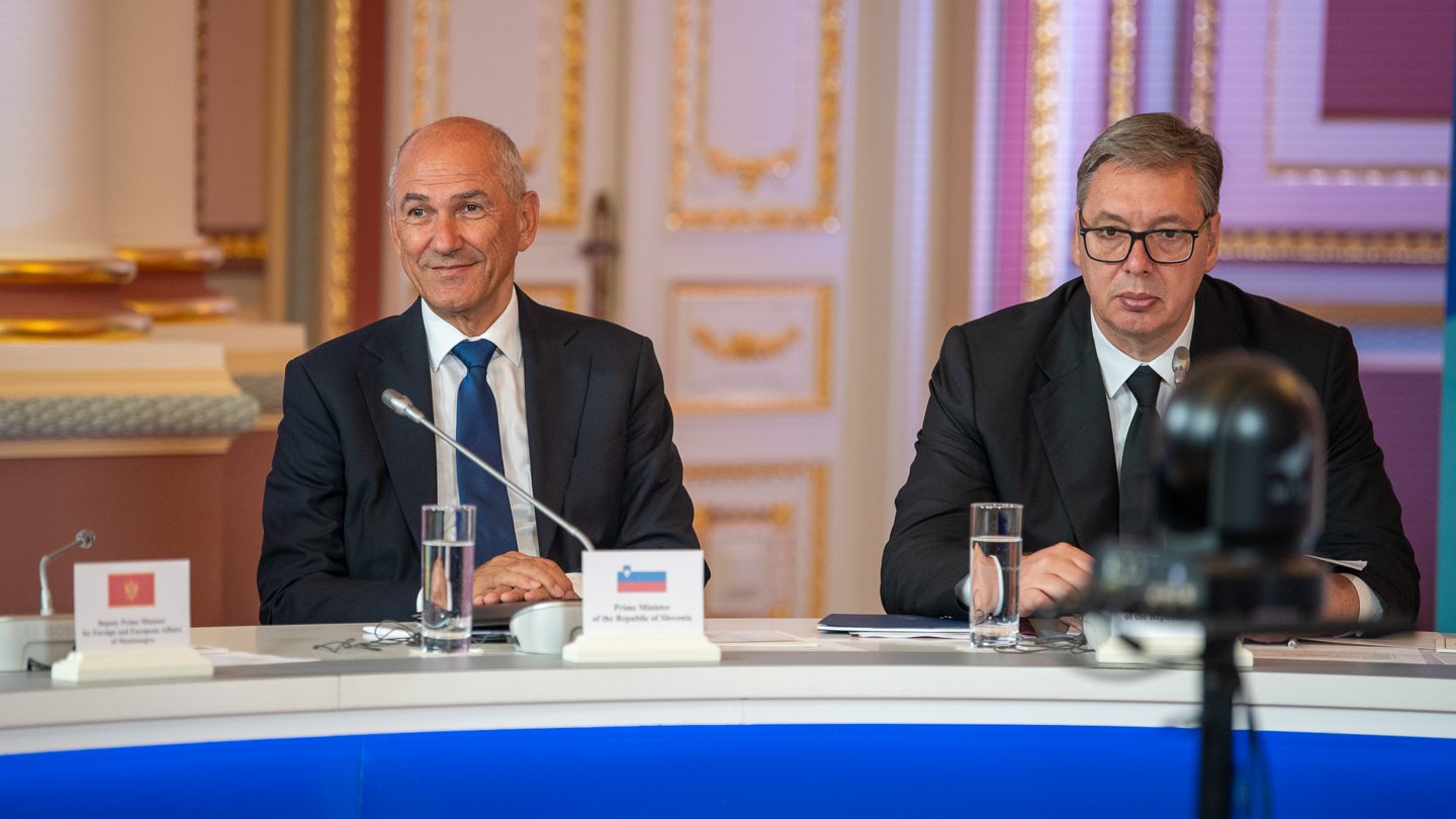 Aleksandar Vučić, in glasses and a dark suit, sits at a conference table beside Slovenian Prime Minister Janez Janša
