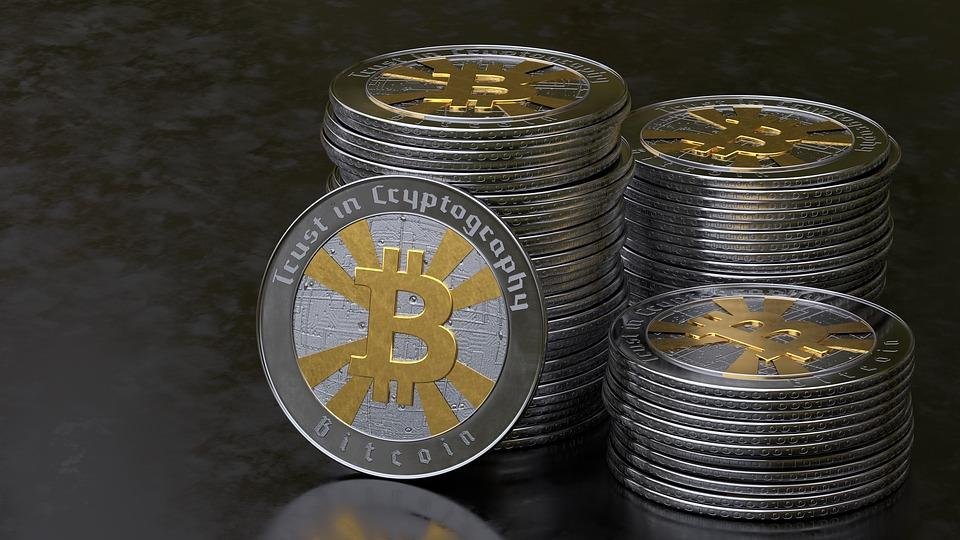 Stacks of silver and gold-coloured physical bitcoin coins on a dark surface