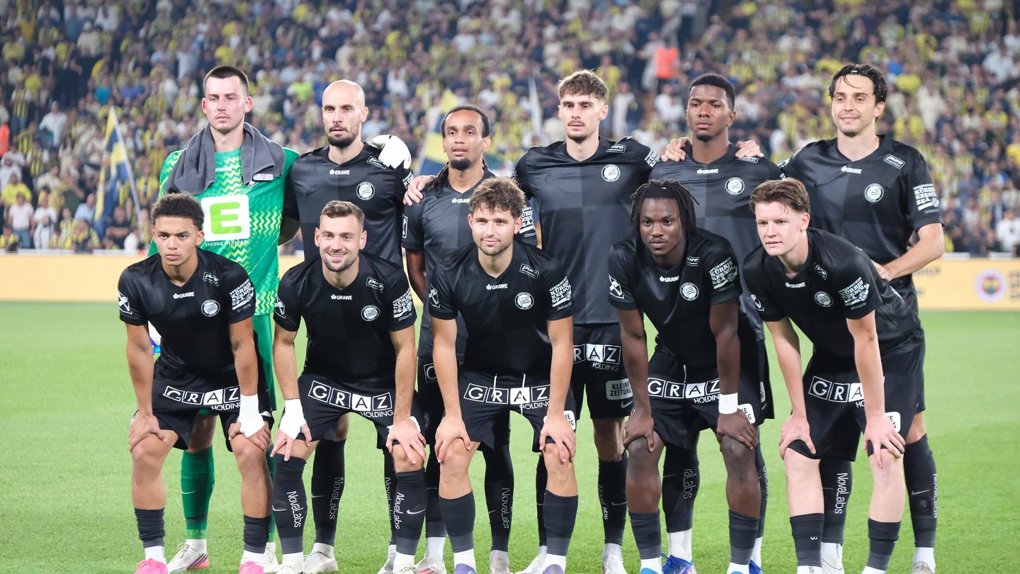 Sturm Graz players in black kits lined up for a team photo on the pitch before a match