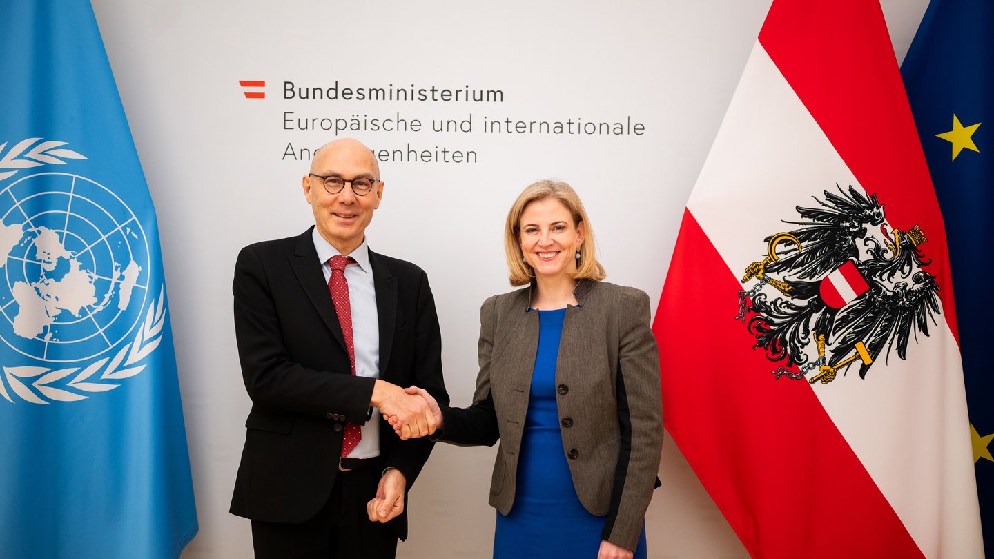 UN High Commissioner for Human Rights Volker Türk shaking hands with Austrian Foreign Minister Beate Meinl-Reisinger in front of UN and Austrian flags