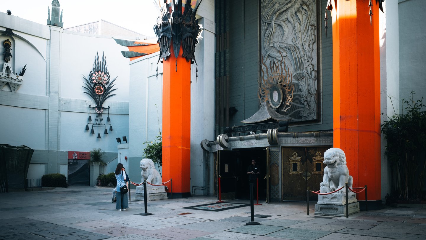 The forecourt of the TCL Chinese Theatre in Hollywood, with its two tall orange columns, stone lion statues and ornate green roof decoration
