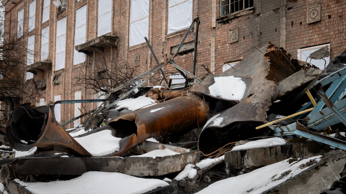 Twisted, burnt metal pipes and concrete slabs covered in snow in front of the damaged brick building of the Darnytska heat and power plant in Kyiv