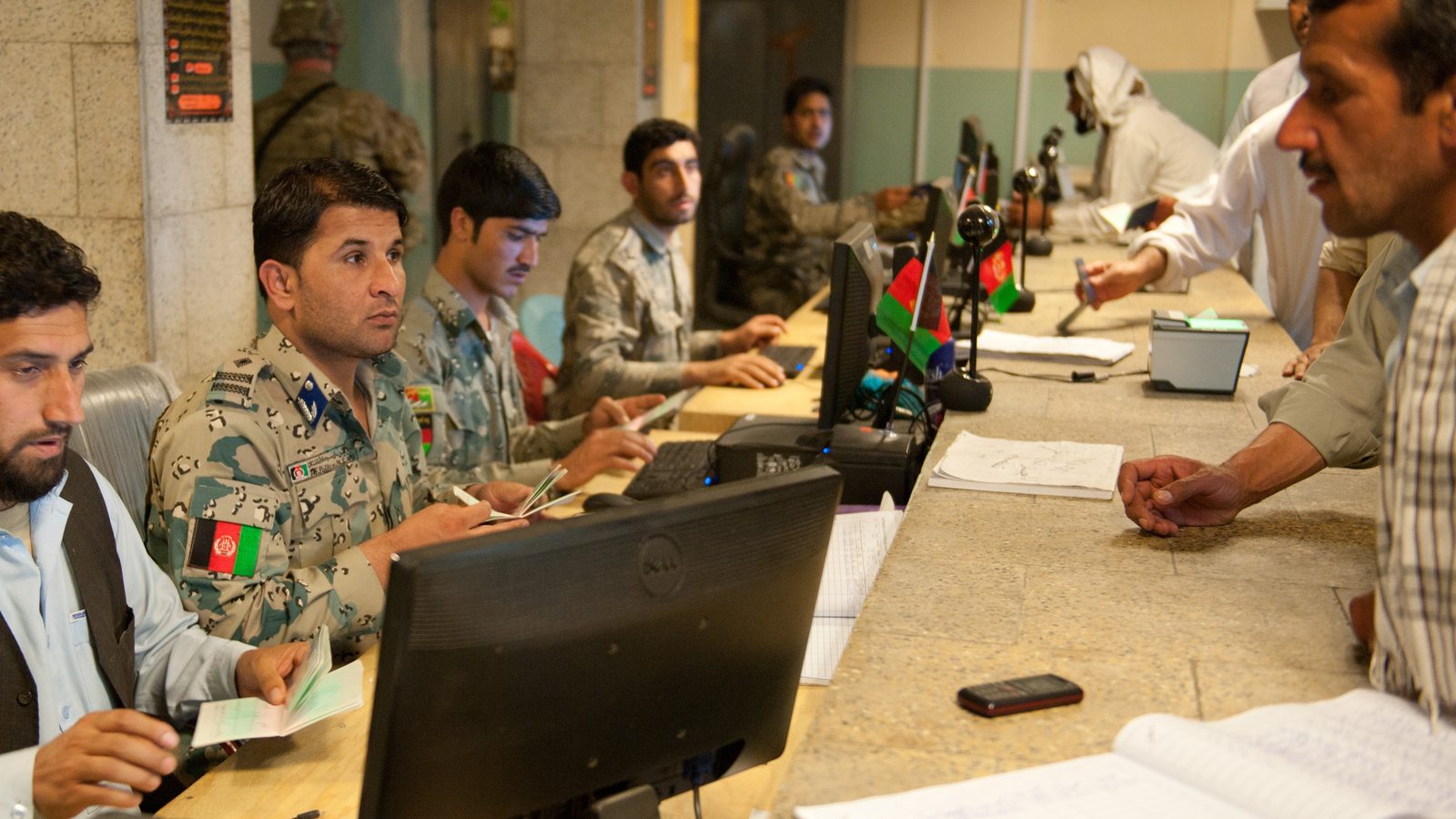 Afghan border and customs officials work at desks and computers inside the Torkham border station