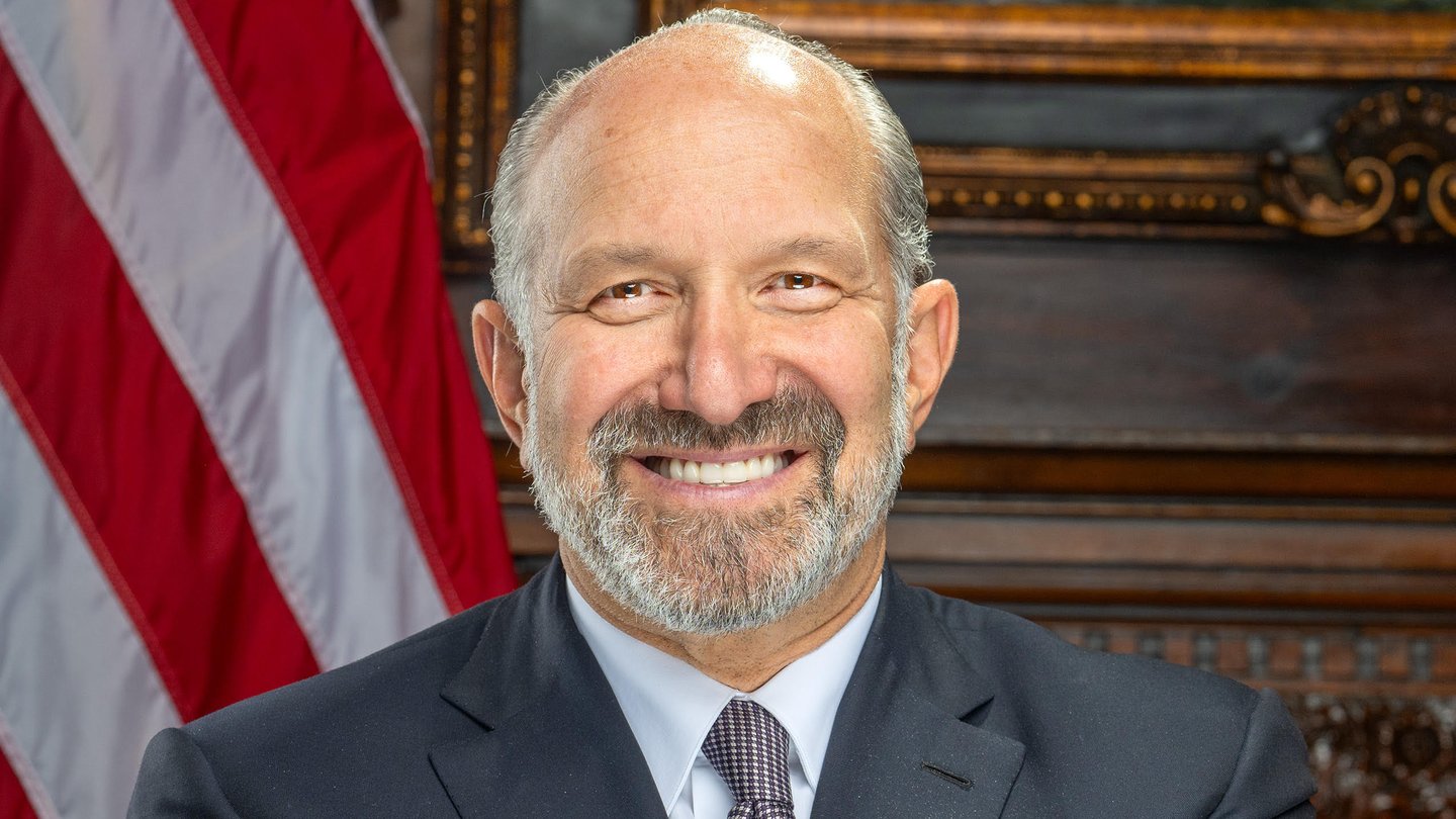 Official portrait of US Commerce Secretary Howard Lutnick in a dark suit in front of a US flag