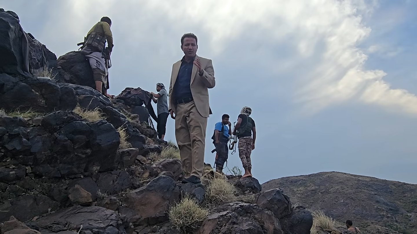 Yemeni government fighters standing on a rocky mountain ridge under a cloudy sky in Jabal Habashi district, Taiz
