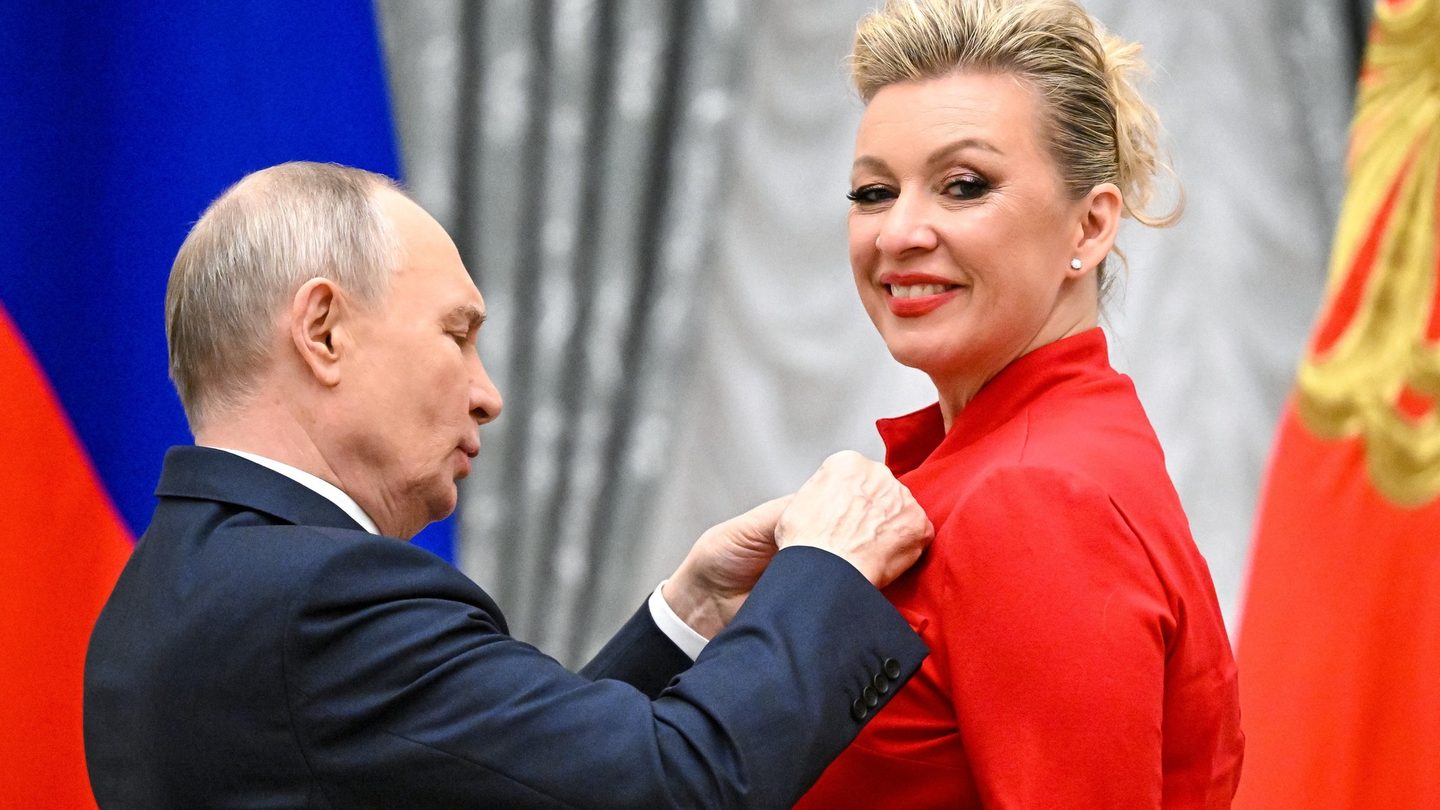 Russian Foreign Ministry spokeswoman Maria Zakharova, in a red jacket, receives a state award from President Vladimir Putin in the Kremlin